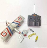 Photo of the assembled RC airplane and its remote control showing design details and included yellow charging cable.