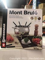 Front of original product box showing fondue pot with forks and accompanying food items.