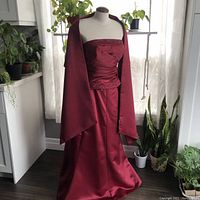 Full view of the red two-piece evening gown displayed on a dress form including the matching stole draped over the mannequin's shoulders.