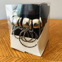 Scarf packaged in original clear box showing silver-tone beads and metal rings.