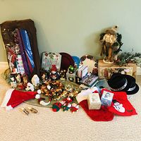 Photo showing a spread of various Christmas figurines, holiday plates, stockings, Santa hats, and decorative pieces.