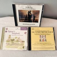 Three CD jewel cases showing Solitudes Algonquin Suite, Nature's Songbook by Hallmark, and CBS Masterworks Dinner Classics The Sunday Brunch Album