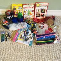 Wide shot showing various kids craft items including books, colorful yarns, beads, foam shapes, pom-poms, sequins, and craft storage containers.