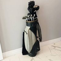 Full view of Fletcher golf bag with several golf clubs inside, standing on floor