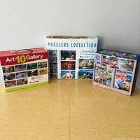 Three puzzle boxes: Art 10 Gallery, Puzzlers Collection, and one with assorted landscapes and scenes.