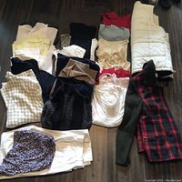Overview of all clothing items arranged on floor including tops, vests, sweaters, and pants