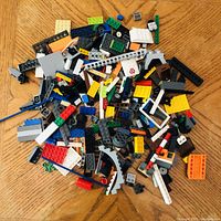 Top-down photo of assorted loose Lego bricks and pieces scattered on a wooden surface.