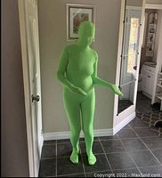 Person wearing chromakey green full-body spandex suit covering entire body including head and feet in standing pose
