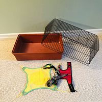 Pet cage components: brown plastic base and black metal wire cage top, shown separately on carpeted floor