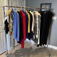 Full view of the women’s clothing hung on a rack showing various styles and sizes including dresses, tops, cardigans, and pants in multiple colors and prints.