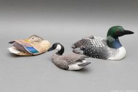 Three bird decoy sculptures on gray background showing full lot including the Loon, Goose, and Mallard