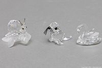 Three crystal figurines: snail on leaf, seal, and swan, clear faceted crystal with details