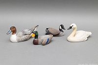 Full view of all four duck decoy sculptures including the Tundra Swan, Pintail, Mallard Drake, and unsigned decoy arranged on flat surface.