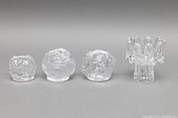 Front view of four clear crystal votive candleholders showing Sunflower design and three Snowball designs.