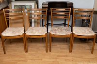 Front view of four walnut ladder-back chairs with upholstered seats