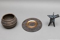 All three items displayed from left: bowl, wall plate, Jue vessel