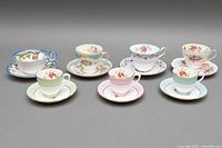All five sets of teacups and saucers arranged together showing various floral patterns and pastel colors.
