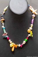 Front view of the multicolored dyed fresh water pearl necklace with assorted gemstone beads displayed on black neck stand.