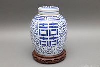 Front and side view of blue and white porcelain ginger jar on carved wooden base