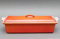 Side view of the closed rectangular orange Le Creuset pâté terrine dish with lid and handles.