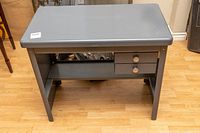 Front angle view of the gray mid century COLE industrial typing table with smooth top, two drawers and shelf visible under top.