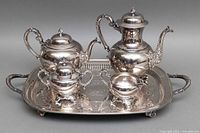 Full view of the 5-piece vintage silver plated tea set on tray, showing teapot, coffee pot, creamer, sugar bowl, and tray with reflective sheen.
