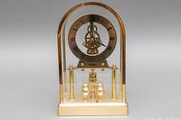 Front view of gold-tone vintage Birks quartz mantle clock with Roman numeral dial and visible gears.
