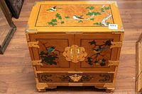 Front view of cabinet showing hand painted bird and floral motifs on doors and top, brass hardware and corner protectors