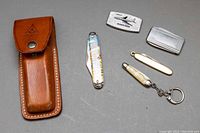 Full set arranged showing leather Scout Secunda pouch and five metal tools including folding knives, pin cutters, and rectangular items.
