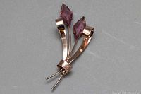 Front view of the rose gold tone sterling silver brooch with two faceted purple diamond-shaped crystals, showing the shape and design details.