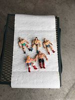 Five mini wrestling bendable action figures laid on white paper towel, showing detailed clothing and physique. Photo taken to show all figures in set.