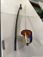 Two right-handed sabres lying on a table with one guard visible, showing length and blade cover