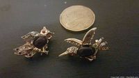Photo showing the two gold tone costume jewelry pins shaped like a hummingbird and an owl, placed next to a coin for size comparison.