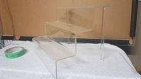 Angle view of the clear plexiglass 4-level display stand showing the step design and clear material.