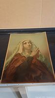 Full image of the vintage religious-themed print showing a praying woman in a cloak and headscarf.