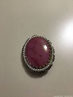 Front of oval Victorian-style brooch showing a pinkish-purple tourmaline chalcedony cabochon surrounded by small pearls
