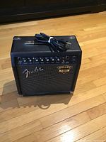 Front view of Fender Bullet 150 amplifier showing control panel, Fender logo, and Bullet badge with power cord coiled on top.