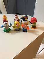 Group of six colorful vintage wind-up toys showing front characters on table.