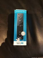 Front view of the blue box showing the Wii Remote Plus controller image and Wii U branding on a black surface.