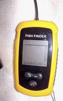 Close-up of the yellow and black portable fish finder device with LCD display and control buttons.