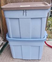 Two blue Rubbermaid Roughneck Rough Tote storage containers stacked, one with brown lid and one with blue lid.