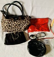 Front view of four vintage ladies purses including two clutches, a leopard print handbag, and a small black round purse.