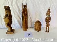 Front view of four African hand carved exotic hardwood sculptures showing different figures including a human figure, a boat shape, a turtle, and an abstract form.