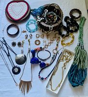 Photo of vintage jewelry collection including necklaces, bracelets, rings, earrings, and jewelry boxes on surface