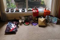 Photo showing four Thomas Kinkade lighted lighthouse figurines aligned on a windowsill, displayed along with various holiday decor items on floor beneath.