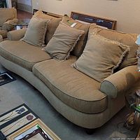 Textured beige upholstered sofa with three matching pillows and rounded armrests