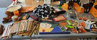 Table with a large assortment of Halloween and fall decorations including painted wooden signs, cutouts, foil pencils, foam stickers, and a candle.