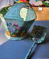 Photo of the hand painted metal coal bucket and matching shovel showing colorful floral artwork and bucket handle.