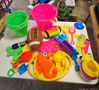 Top view photo showing all outdoor play items including buckets, football, water pistols, sand shovels, rake, and sand molds.