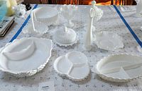 Ten pieces of vintage white milk glass with hobnail pattern, arranged on table.